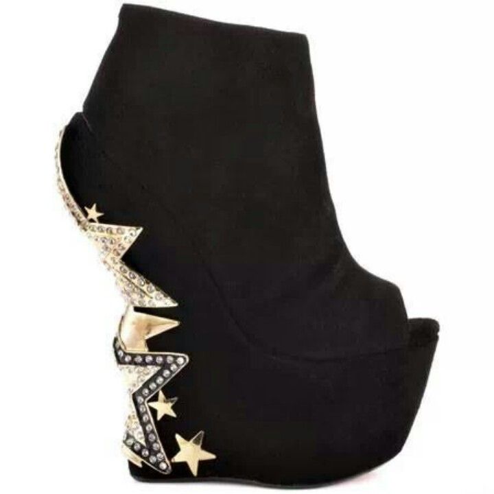 a black ankle boot with a peep toe and a thick platform sole. the boot features a sculptural heel adorned with starshaped embellishments, rhinestone accents, and goldcolored details. the overall aesthetic is unconventional and fashionable.