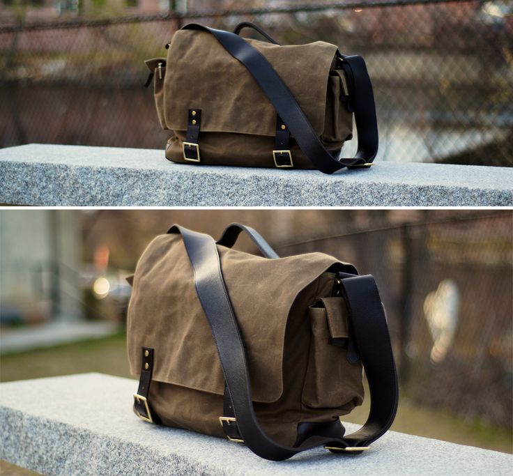 a brown canvas messenger bag with a leather strap sits on a gray stone surface. the bag has a flap that closes with a buckle and has a smaller pocket on the front. the bag is in a setting that appears to be urban.