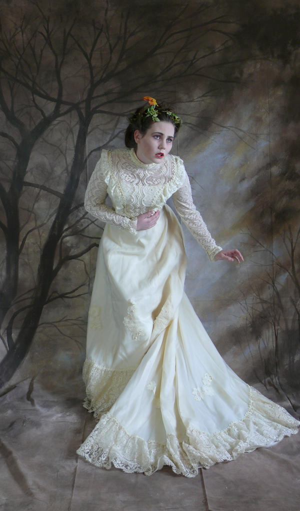 a fulllength portrait of a woman in an antique, ivorycolored lace wedding dress.  she stands against a backdrop of painted dark trees, creating a moody atmosphere. the woman has flowers in her hair and her expression is one of worry or sadness. the dress has intricate lace detailing and a long train. the overall style is artistic and evocative, suggesting a sense of timelessness and melancholy.