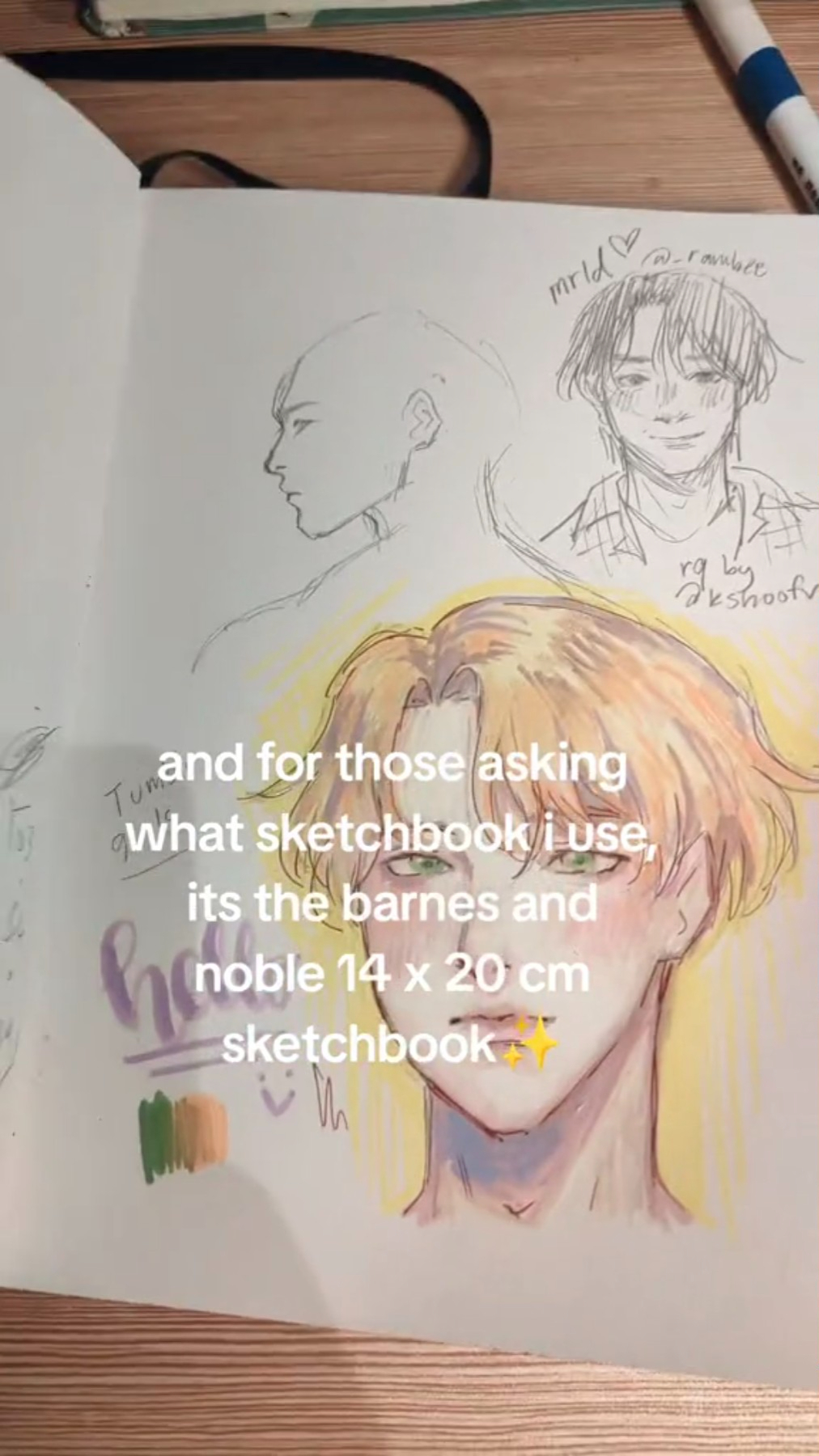 a drawing of a person with a sketchbook. the text "and for those asking what sketchbook i use, its the barnes and noble 14 x 20 cm sketchbook" is written on the page. the drawing is done in pencil and coloured pencils. there is a little yellow star sticker in the lower right corner of the page.