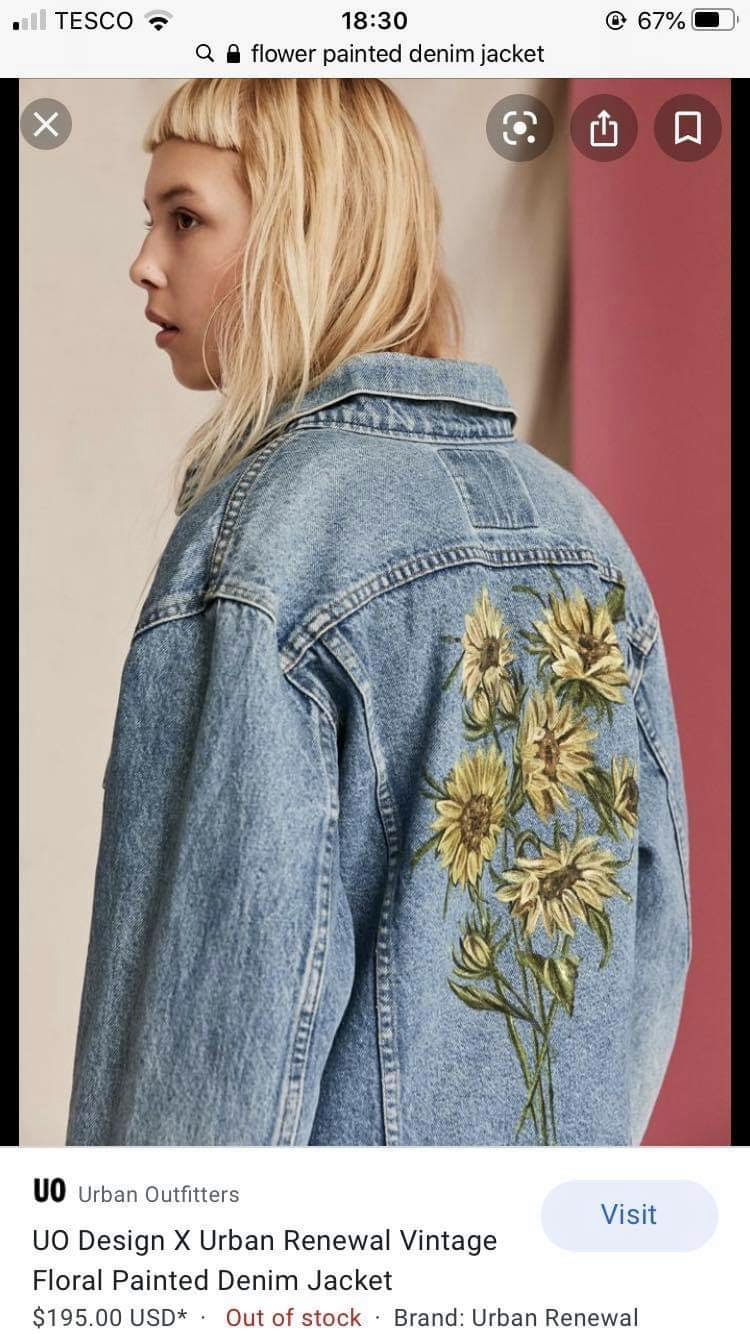 a young woman with blonde hair is modeling a denim jacket. the jacket features a large floral design of sunflowers painted on the back. the image appears to be a product photo for an online clothing retailer, as indicated by the "urban outfitters" logo and "visit" button at the bottom of the image. the overall style of the jacket and the model suggests a vintage or bohemian aesthetic.
