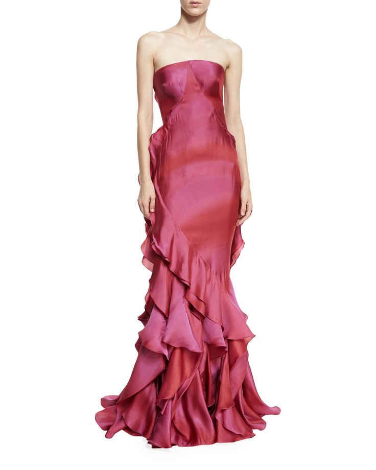 a woman wearing a strapless, floorlength gown in shades of pink and red with ruffled detailing.