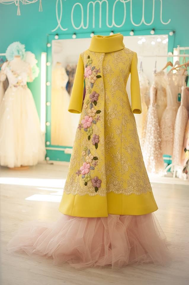 a full shot of a yellow and pink couture gown on a mannequin in a dress shop.