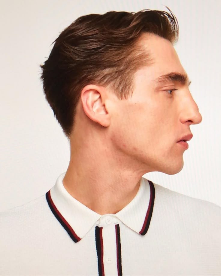 a profile portrait of a fairskinned man with brown hair wearing a white polo shirt with maroon and navy trim. the man is facing to the right.