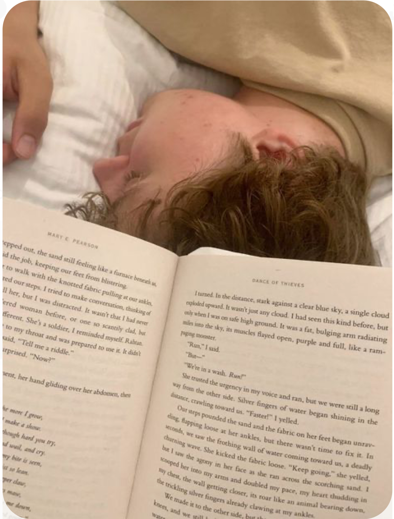 the image captures a tender moment between two young adults lying closely on a bed. the focus is on their upper bodies, with one person's face partially obscured by a book they're reading. the other person's face is turned towards us, eyes closed in peaceful slumber. warm, natural light bathes the scene, highlighting the soft textures of the bed linens and the book pages. the overall ambiance is one of tranquility, intimacy, and shared comfort.