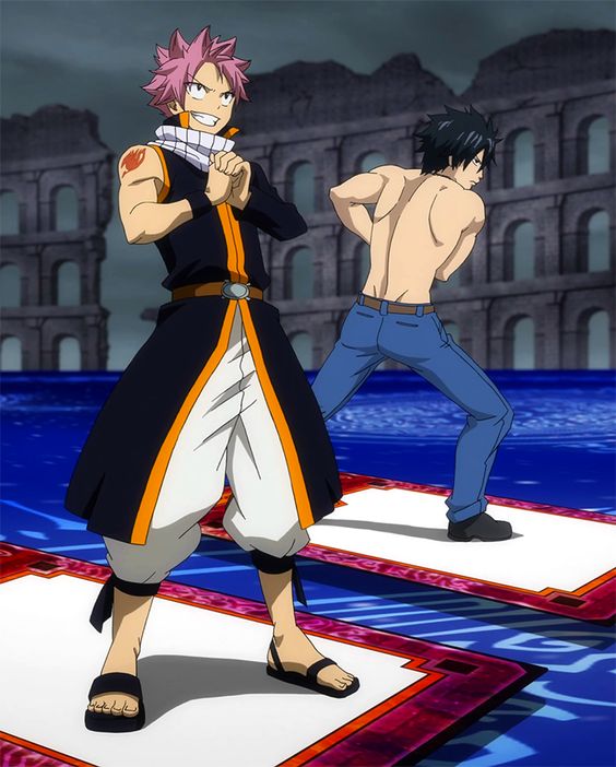two anime characters are facing off in a magical battle. the character on the left has pink hair and is wearing a black, orange, and white outfit. he has a determined expression on his face. the character on the right has black hair and is shirtless, wearing blue jeans. he is stretching his arms behind his back. they are both standing on separate platforms over water, with the ruins of a colosseum in the background.