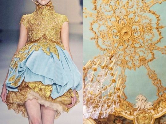 the image shows a woman wearing a blue and gold dress. the dress is ornate and has gold lace and frills. the woman is standing in front of a gold and blue ceiling with a chandelier hanging from it.  the image is elegant and royal.