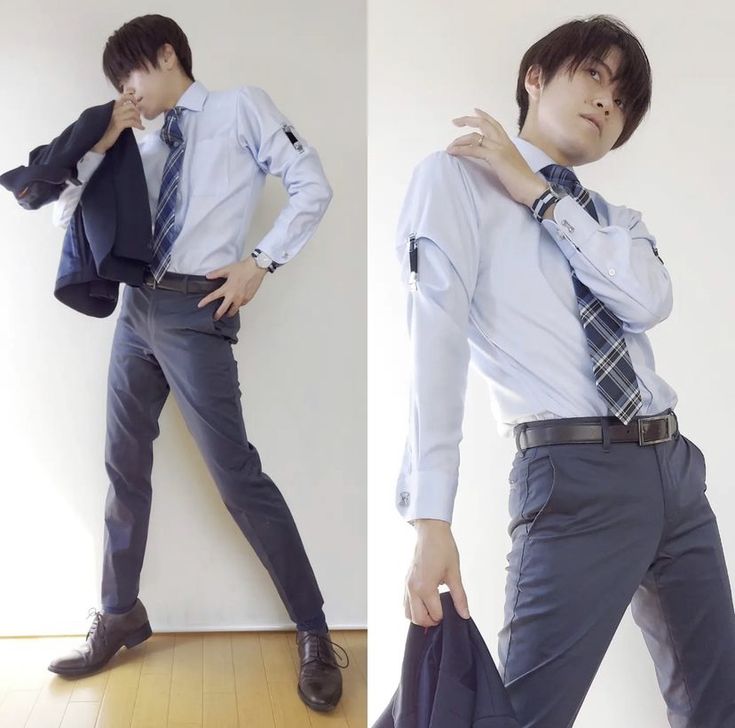 a young man is posing in a blue shirt, blue pants, a brown blazer, a black tie, and brown shoes. he has a cool and handsome look. the man is standing against a white background and the lighting is welllit. the photo was taken indoors.
