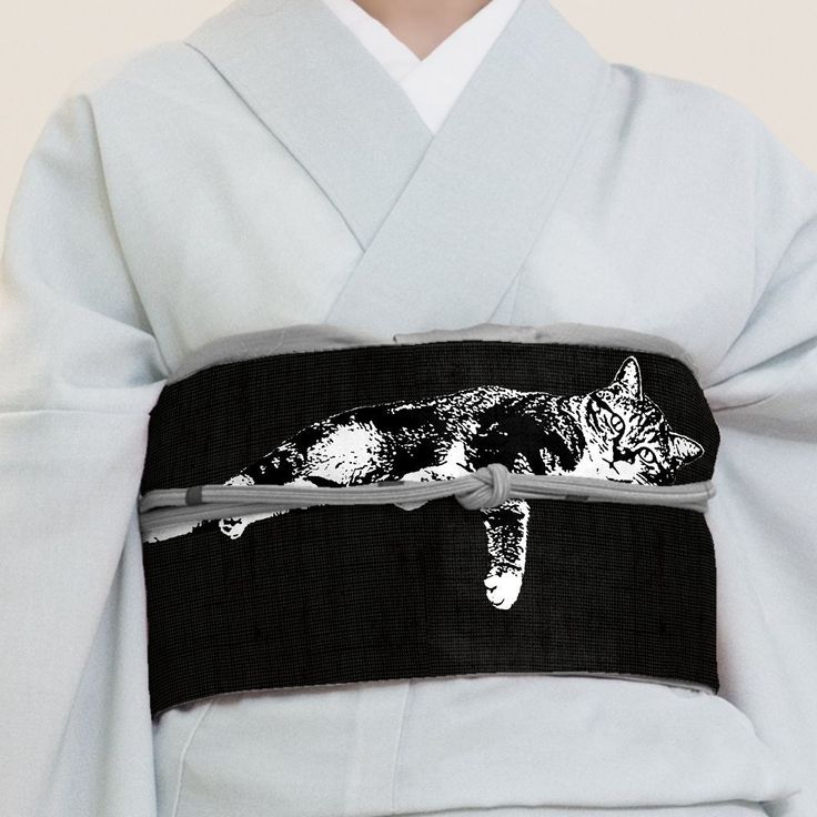a person wearing a light gray kimono with a wide black obi featuring a black and white illustration of a lounging cat. the obi is secured with a light gray cord tied in a knot.
