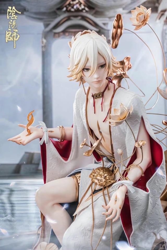 a stunning figurine of an anime character, possibly a male deity or spirit, dressed in a flowing white kimono adorned with gold and red accents. the figurine is surrounded by intricate details including lotus flowers, gold chains, and a delicately sculpted face. the overall image evokes a sense of ethereal beauty and mystique.