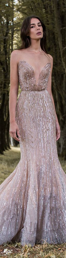 a woman in a sparkling sequin gown is posing in a forest setting. her hair is styled and she has a natural makeup look. the dress has a deep vneckline and a mermaid silhouette. she is looking at the camera with a confident expression.  this photo is a beautiful and elegant portrait of a woman in a glamorous outfit. the lighting and composition create a romantic and dreamy atmosphere.