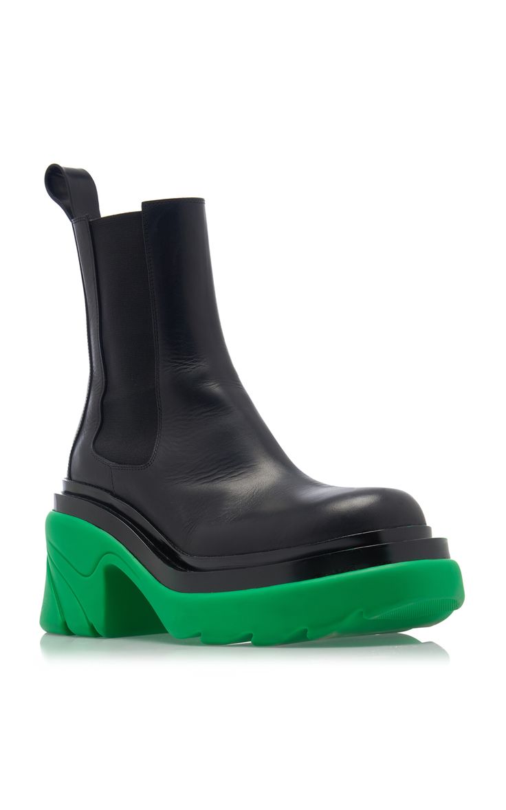 a closeup shot of a women's black leather chelsea boot with a vibrant green platform sole. the boot is sleek and stylish, with a slightly pointed toe and a comfortablelooking fit. the green sole adds a bold pop of color, creating a contemporary and fashionable look. the image is set against a clean white background, making the boots the focal point.