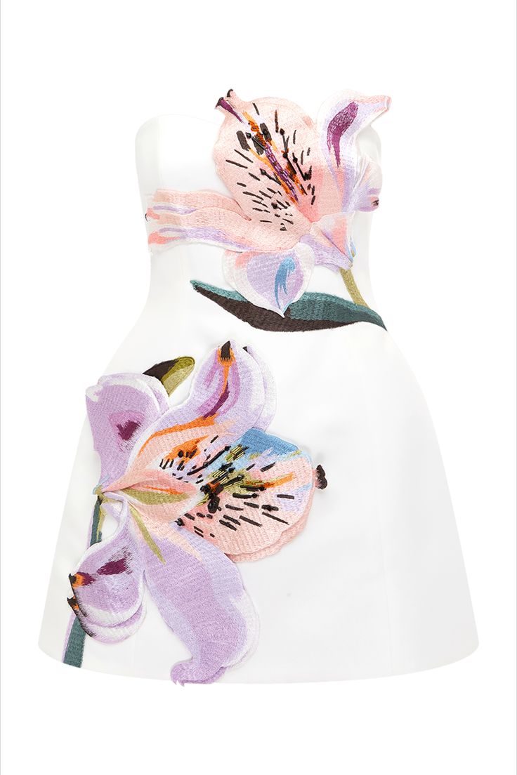 a white strapless aline dress with floral appliqués and embroidery. the dress has two large alstroemeria flower designs on it. one is near the top right, and the other is on the bottom left. the flowers are shades of pink, purple, and blue.