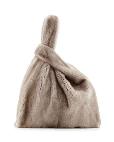 a soft, fluffy, beige fur tote bag with a knotted handle. the bag is a fashion accessory perfect for a luxurious look.