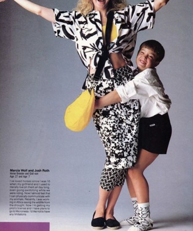 a photo of a woman and a child hugging. the woman has patterned clothing, a yellow fanny pack, and her arms are up. the child has black shorts, a white shirt, patterned socks, and tennis shoes. the photo looks like it came from the 1980s.