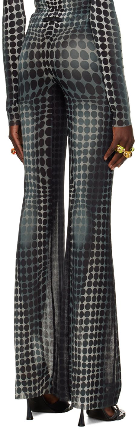 a woman wearing a pair of black and white polka dot pants. the pants are wide leg and high waisted. the woman is wearing the pants with a black shirt.
