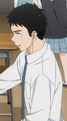 he image shows a young man, likely an anime character, from the side. he wears a white shortsleeved shirt with a breast pocket, a dark blue tie, and what appears to be gray pants. his black hair is short, and he has a determined expression. the setting seems to be inside a school, judging by the desk and the glimpse of another student's plaid skirt in the background. the lighting is bright, illuminating the scene clearly.