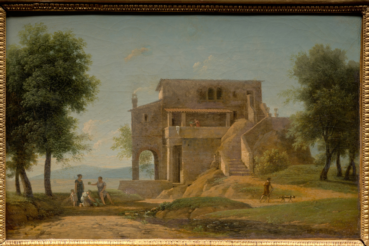 this is a painting depicting a rural landscape. a stone building with an arched entrance and a staircase leading to an upper level dominates the scene. figures are present near the building, suggesting everyday life. a stream flows in the foreground, and trees frame the composition. a man walks with a dog on a path to the right. the painting is framed.