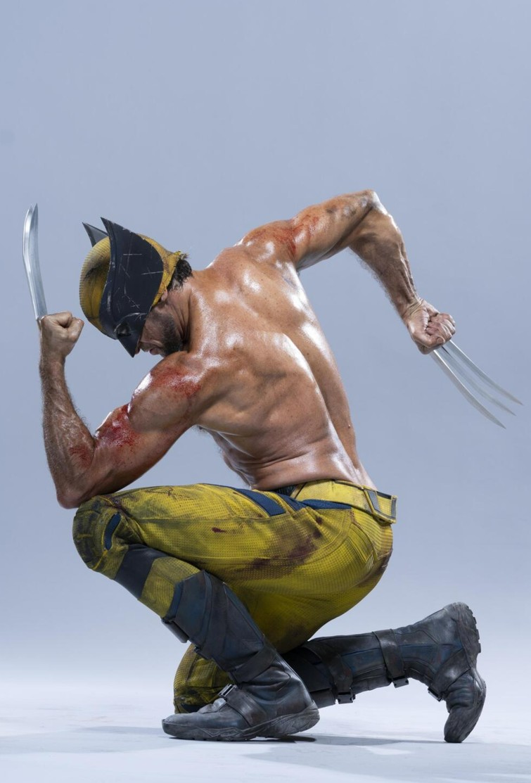 the image shows a muscular man dressed as the superhero wolverine, crouching and holding his iconic claws. he wears a yellow and black mask and matching pants with black boots. he has blood on his upper arms.