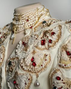 a closeup shot of a white beaded dress featuring elaborate pearl and lace embellishments. the dress is adorned with a stunning necklace of pearls, and is meticulously crafted with intricate details. the image captures the elegance and sophistication of the garment, highlighting the beauty of intricate design and craftsmanship.