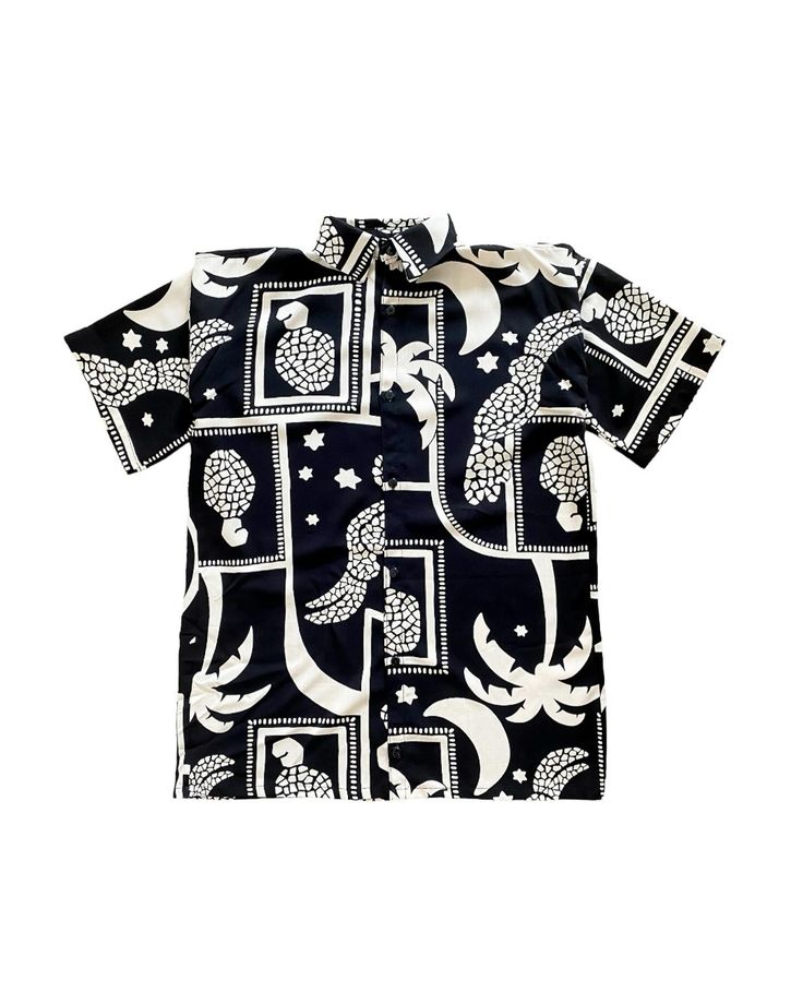a black and white patterned shortsleeved buttondown shirt is displayed against a white background. the shirt features a tropical pattern with turtles, moons, palm trees, and stars in both square frames and standalone images.