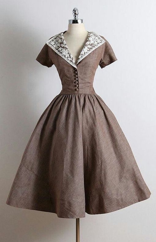 a brown vintage dress with a lace collar is shown on a mannequin. the dress has a full skirt, a fitted bodice, and short sleeves. the dress is photographed against a white background in a studio setting.