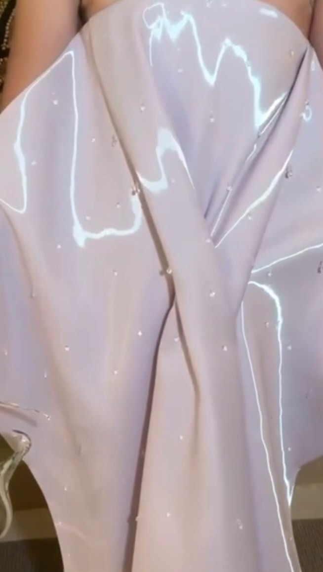 a closeup image shows a light pink fabric draped with beads scattered across it. light reflections add a shiny texture to the fabric.
