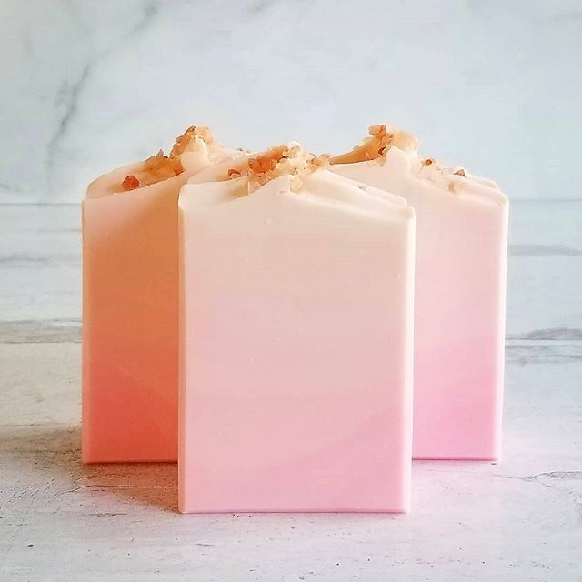 three bars of pink and white handmade soap with a hint of gold on top. the soap is sitting on a white marble countertop.