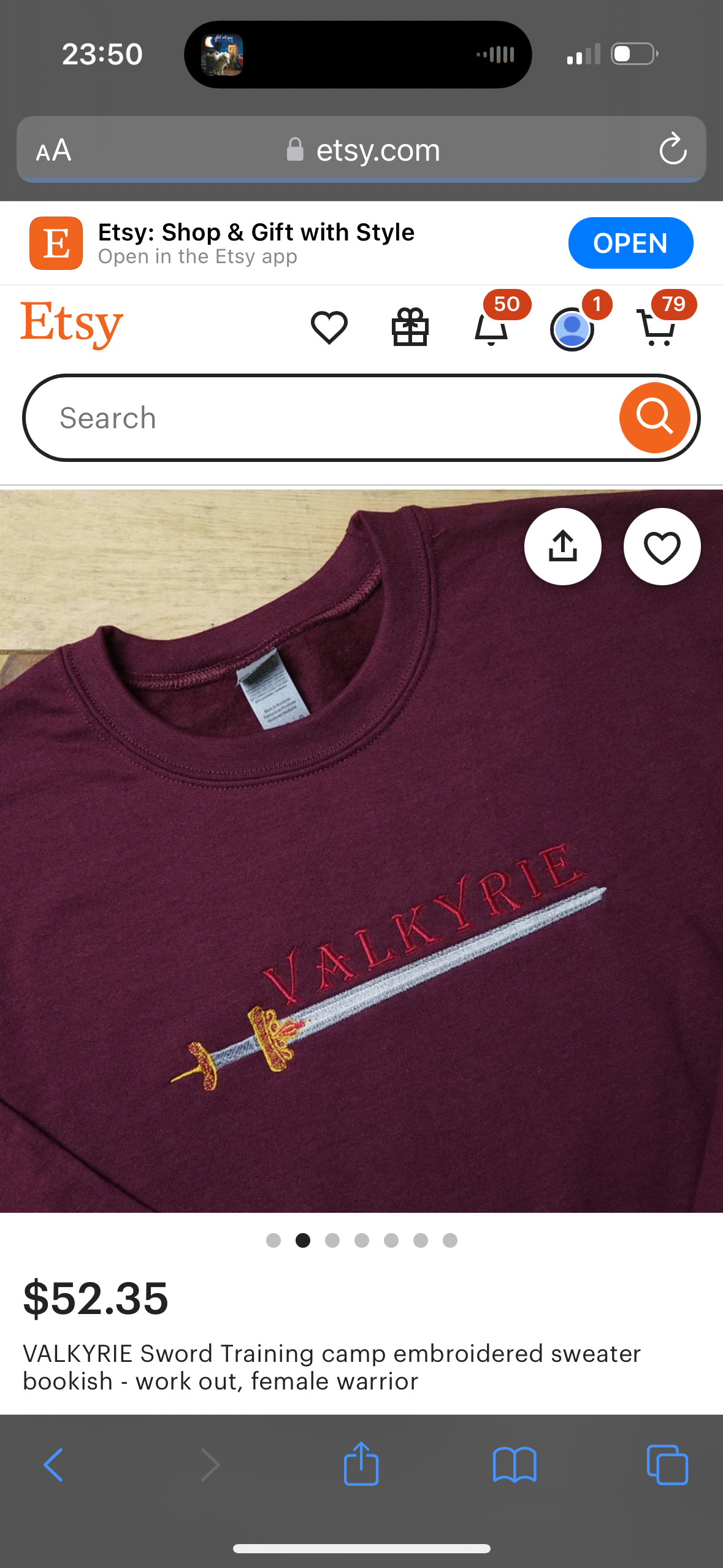 this is a closeup image of a crimson red embroidered sweater that says "valkyrie" and has an image of a sword on the front. the image is taken on a phone's screen which shows the product listing for the sweater on etsy. the listing is titled "valkyrie sword training camp embroidered sweater bookish work out, female warrior" and is priced at $52.35. there are 5 dots below the image to navigate between other images of the product. the bottom part of the phone's screen is visible, showing the back and forward buttons, a download button, a bookmark button and a button to open the folder.