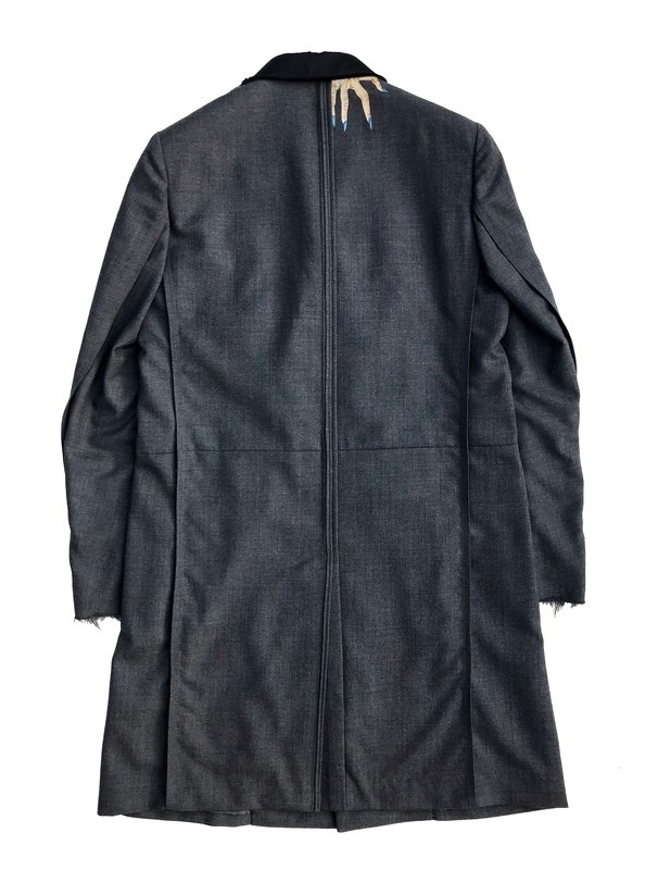 the image shows the back of a long, gray coat with ripped edges at the bottom. the coat is made of a textured fabric and has a single vent in the back. the collar is black and appears to be made of a different material. there is a small, decorative element on the back of the collar.