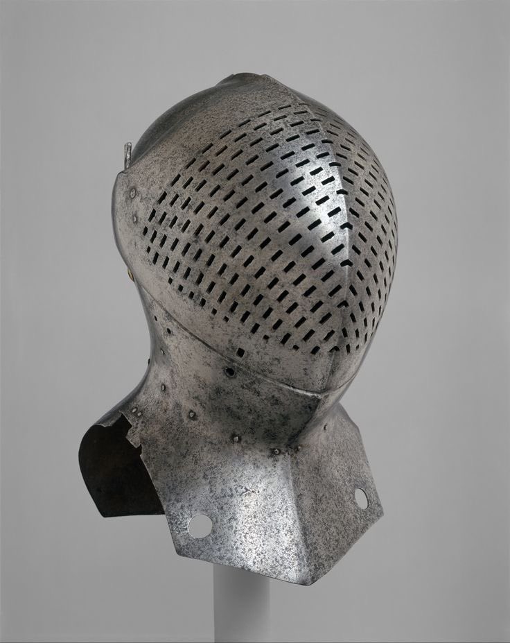 this is a closeup view of a 16thcentury german helmet, crafted from steel. the helmet features a distinctive design with numerous small holes perforating the upper portion, likely intended for ventilation. the metallic surface displays a blend of gray and silver tones, reflecting the ambient light of the indoor setting.  the helmet is displayed on a minimalist white stand, emphasizing its historical and artistic significance.