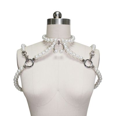 a mannequin is wearing a body harness made of pearls, with metal rings and clasps. there is a pearl necklace at the top of the mannequin.