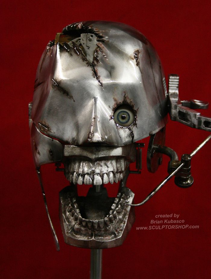 a silver skull with one eye, metal teeth, and a damaged, mechanical face. the skull sits on a black stand, with the red background.  the image is a surreal, almost disturbing reminder of the intersection of technology and humanity.