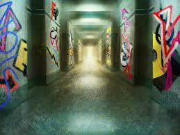 the image shows a long, dark hallway covered in colorful graffiti. the walls are dirty and worn, and the light at the end of the hallway is bright and inviting. the graffiti is mostly abstract and geometric, with some letters and symbols thrown in. the image creates a sense of mystery and intrigue, as if the viewer is about to enter a dangerous and exciting world.