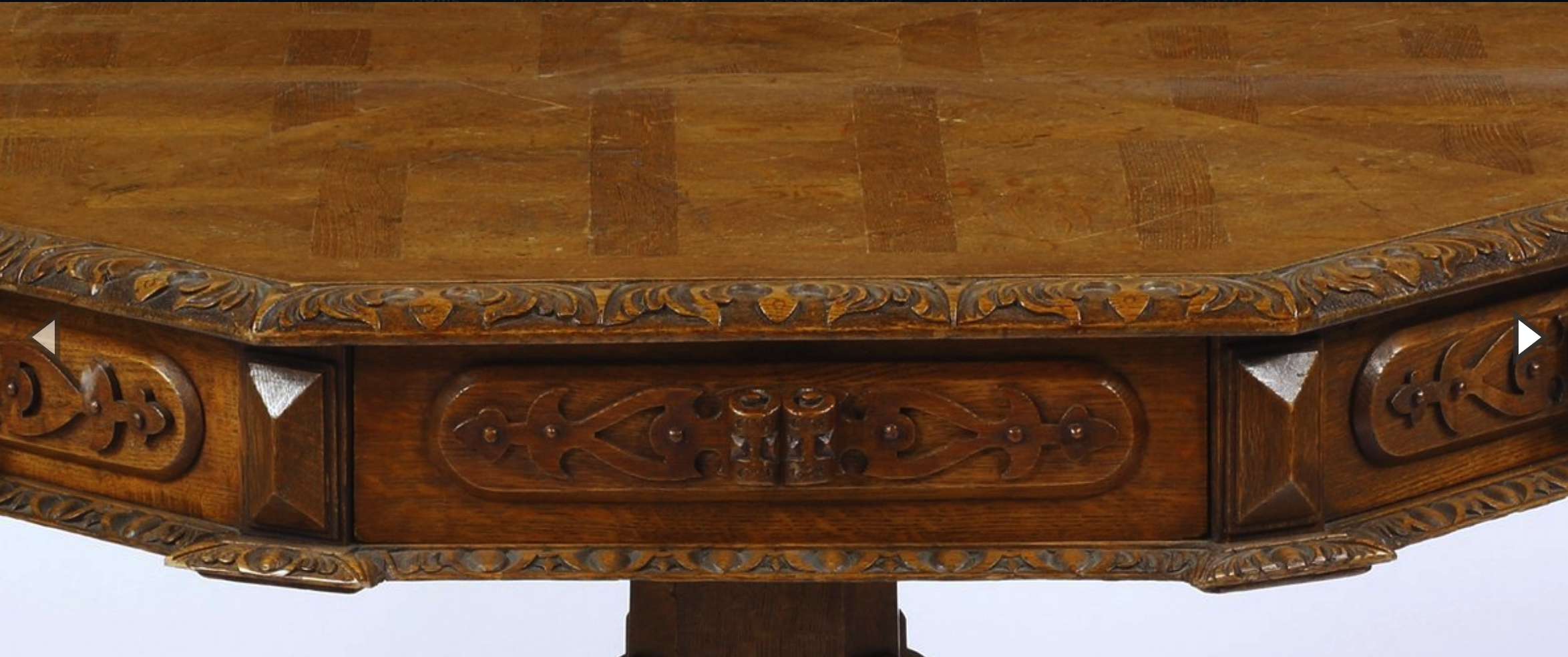 this image features a closeup view of an antique wooden table. the table top is made of wood that has been carved into an intricate pattern, and the edges of the table are also carved with a decorative design. the table appears to be in good condition, and the craftsmanship is evident in the intricate details. the image captures the beauty of antique furniture and the skill of the craftsman who created it.