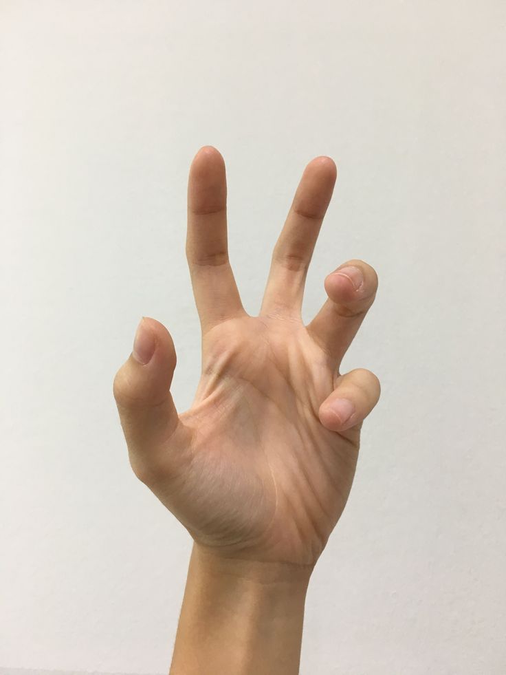 a closeup of a hand, showing a gesture of making a "peace" sign with the index and middle finger while the other fingers are curled inwards. the hand is in focus against a blurry white background.