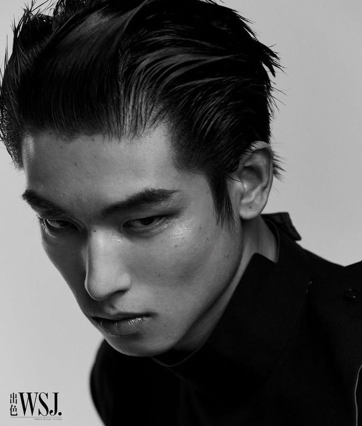 a black and white portrait of a man with slicked back hair, wearing a black jacket. he is looking down and to the side, with a serious expression on his face. the image is from the wsj magazine.