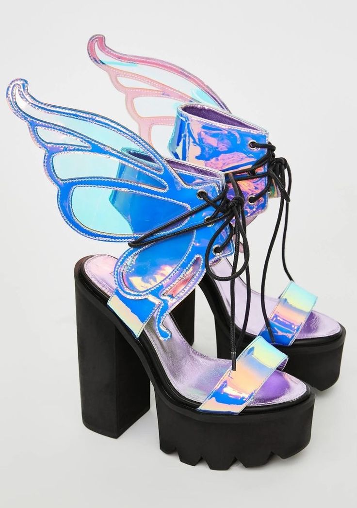 a pair of women's iridescent platform sandals with large butterfly wings on the sides. the sandals are laceup and have a chunky platform heel. the iridescent material shimmers with blue, pink, and purple hues. the shoes are positioned against a white background.
