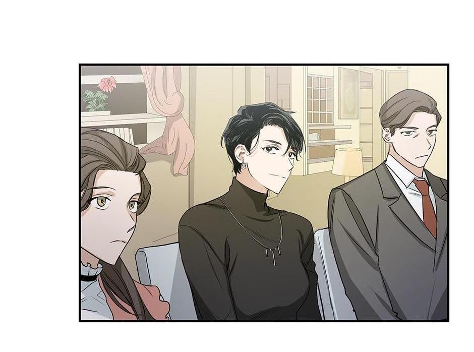 he image shows a scene from a manhwa or webtoon. three characters are depicted sitting in a room. a woman with brown hair is on the left, a person with short black hair in the center, and a man with brown hair in a suit on the right. the setting appears to be a formal or upscale home. the characters look to be engaged in a conversation or discussion. the art style is clean and simple, with a muted color palette.