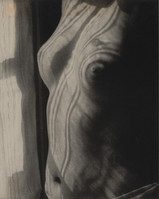 the image is a closeup, monochrome photograph of a female torso. the lighting is dramatic, using chiaroscuro to create strong contrasts between light and shadow, highlighting the texture and curves of the body.  the folds and lines of the skin are emphasized, giving the image an almost abstract quality.  the overall mood is dark and sensual, with the subject appearing partially obscured by shadow. the background is blurry and indistinct, drawing focus to the form of the torso.