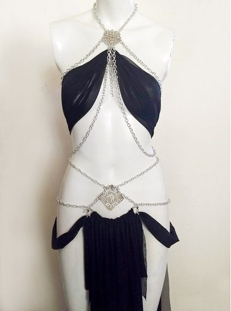 a mannequin is wearing a black garment with a silver chain body jewelry. the garment consists of a black mesh top and bottom with silver chains connecting them. the chains are adorned with silver floral embellishments.