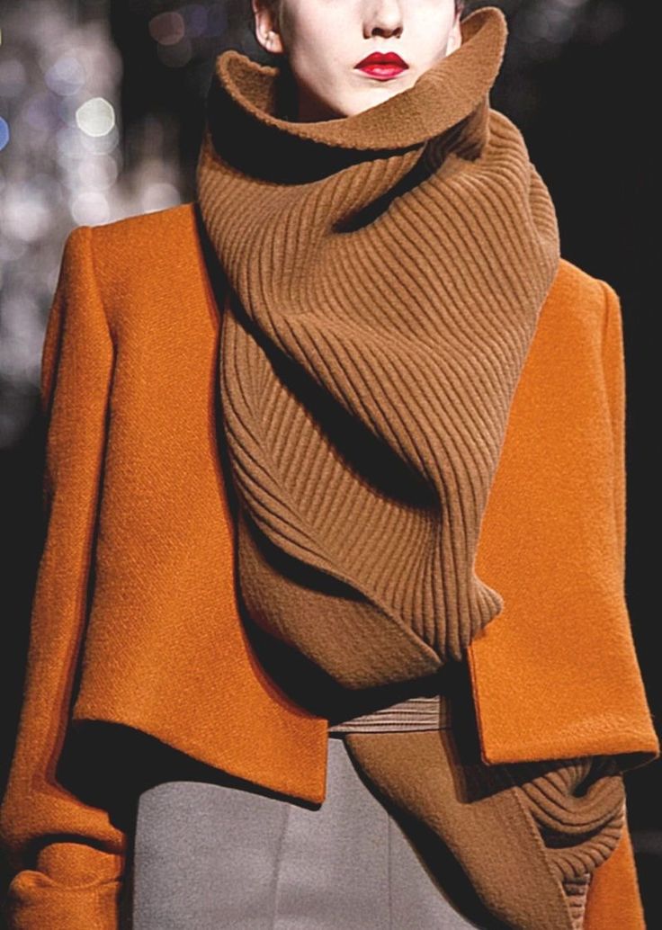 a woman in a brown scarf and orange jacket, runway fashion.