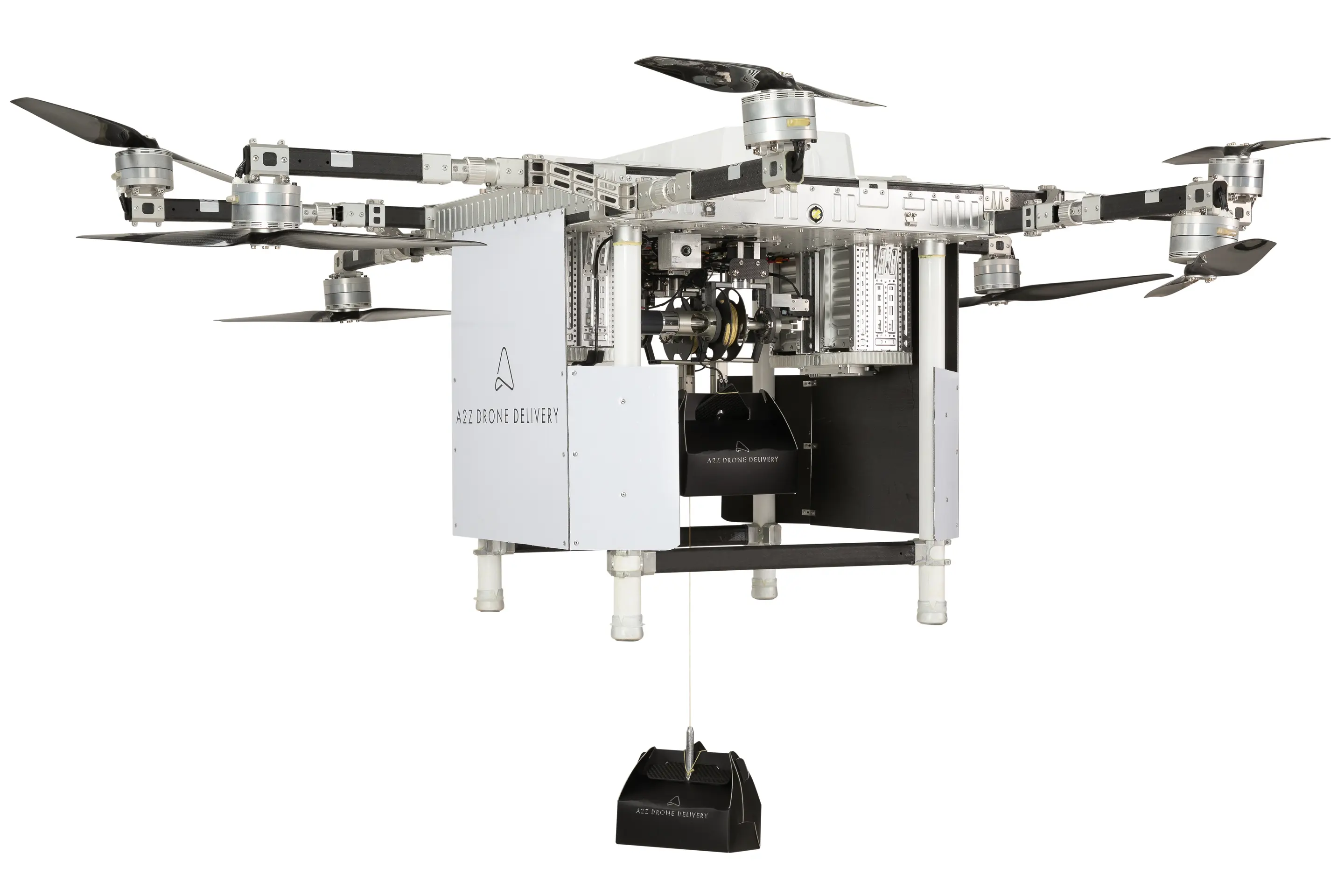 a22 drone delivery service drone with black and white colors, and hanging package container. it has six propellers in total. the drone has a black box in the center with multiple metal elements attached to it. it is designed for carrying package delivery and appears futuristic.