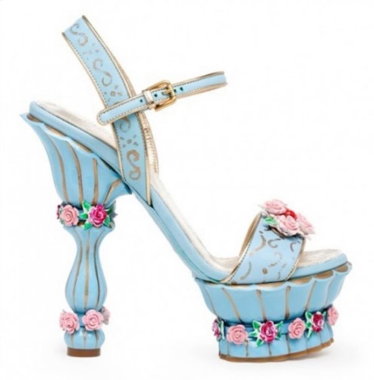 a pair of sky blue floral platform sandals.  the sandals have a delicate strap across the ankle with a gold buckle and a flower design on the side.  the heel is sky blue and shaped like a flower pot with floral embellishments around the top and bottom.  the platform is also adorned with floral accents.  the sandals are a statement piece that would add a touch of whimsy to any outfit.