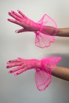 a pair of pink sheer gloves with tulle ruffles on each wrist. the gloves are on the hands of a person. the gloves are soft and delicate, adding a touch of femininity to any outfit. the gloves are perfect for a special occasion or for everyday wear.