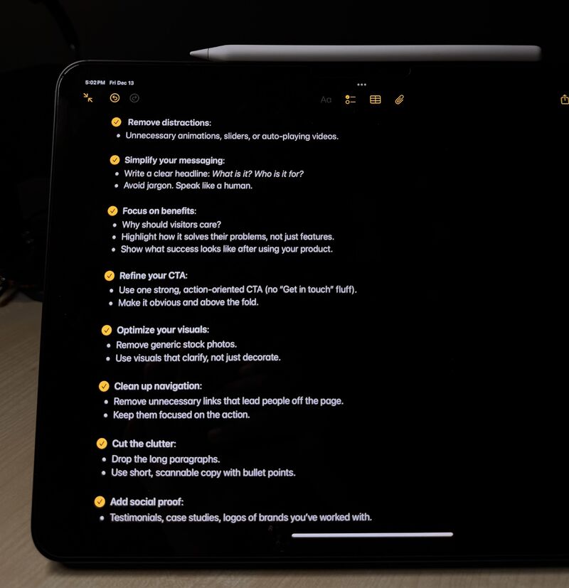 the image shows an ipad screen displaying a checklist of best practices for website optimization. the checklist covers several key aspects including removing distractions, simplifying messaging, focusing on benefits, refining the calltoaction (cta), optimizing visuals, cleaning up navigation, cutting clutter and adding social proof.  the checklist is written in a clear and concise manner with bullet points. a stylus (apple pencil) is resting on the ipad. the overall lighting is dark, emphasizing the screen content.