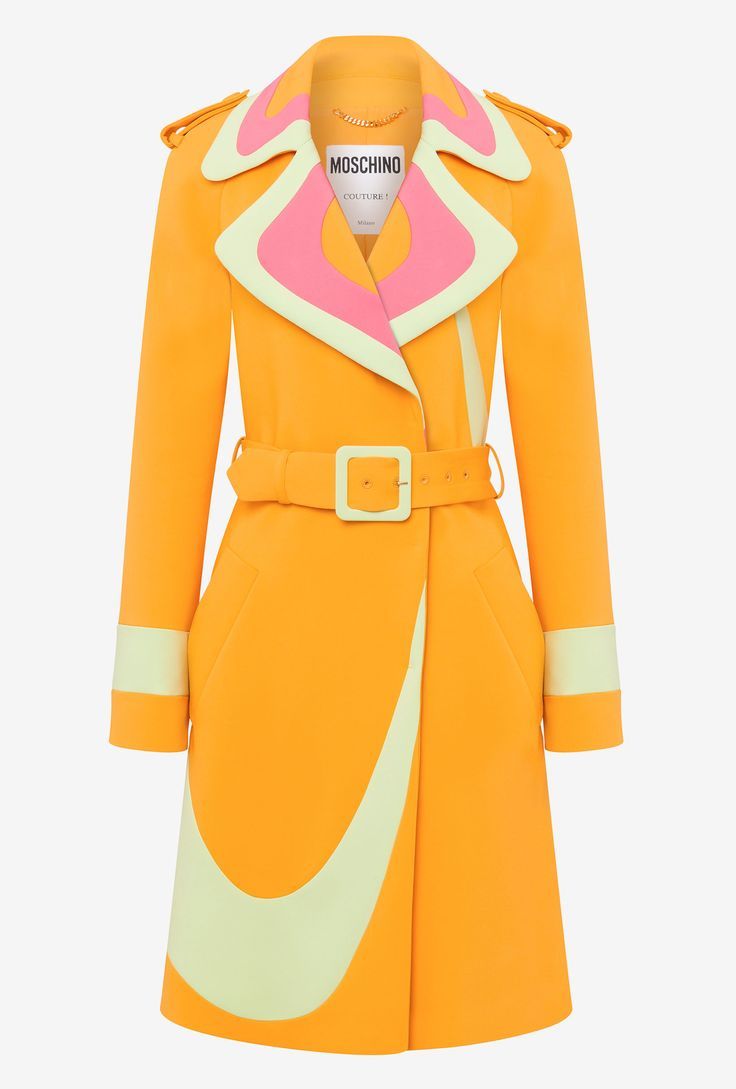 a brightly colored women's trench coat is displayed against a plain white background. the coat is predominantly orange and has a belted waist with a square buckle. the coat's collar is layered with a pink and light green trim. the sleeves end with a light green cuff, and a large light green curve, reminiscent of the nike swoosh logo, adorns the front of the coat. a small label with the words "moschino couture" is visible on the coat near the collar.