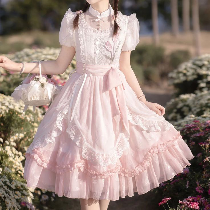 the image showcases a young woman wearing an elegant pink lolita fashion dress. she stands gracefully in a garden, bathed in soft natural daylight. the dress features delicate floral embroidery, intricate lace trim, and a flowing, romantic silhouette. the soft pink hues of the dress complement the blooming flowers and lush greenery of the garden setting.