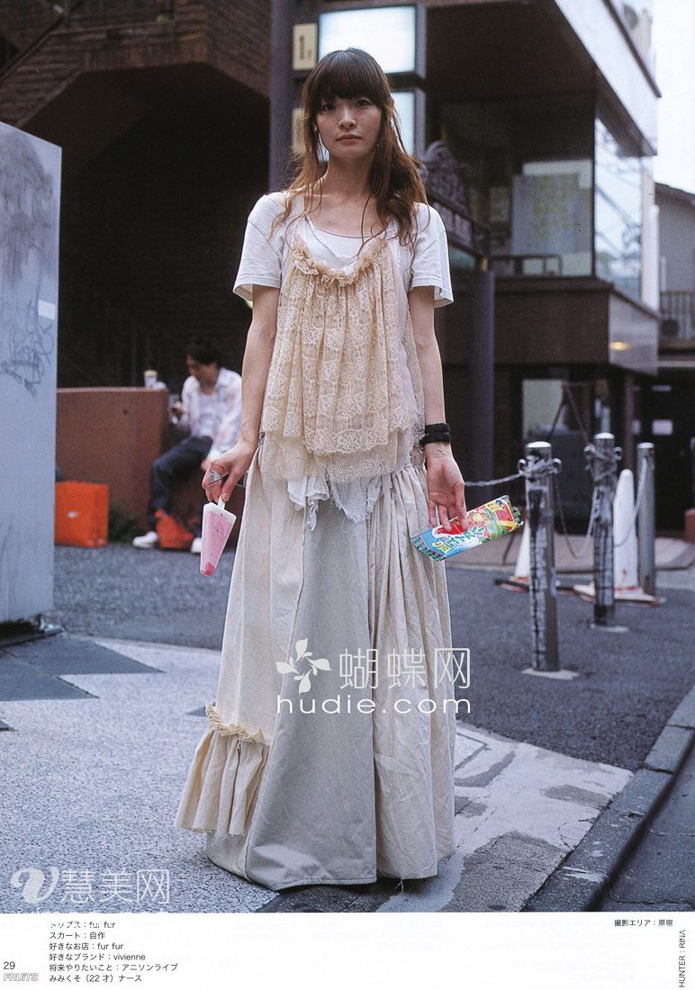 a young japanese woman is posing for a street style photo. she's wearing a white maxi skirt with ruffles on the bottom, paired with a white tshirt and a creamcolored lace camisole. she accessorizes with long necklaces and bracelets. the background showcases a typical japanese street scene, hinting at a vibrant urban environment.