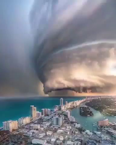 a breathtaking aerial view of a city skyline with dramatic storm clouds overhead. the city is situated along a beautiful coastline, with the ocean stretching out to the horizon. the storm clouds are a dramatic and aweinspiring sight, casting a dark shadow over the city below. the image captures a moment of intense weather, but also the resilience and beauty of the city. the buildings are strong and enduring, standing tall against the elements. the ocean is vast and powerful, yet also a source of beauty and wonder. the image is a reminder of the power of nature and the resilience of humanity.